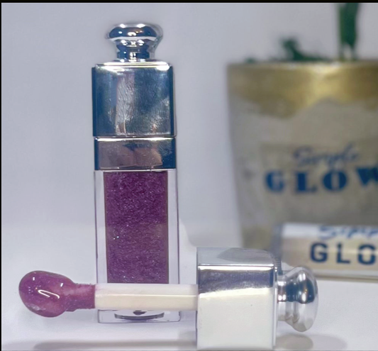 Lip gloss with purple shade and silver cap on a white background