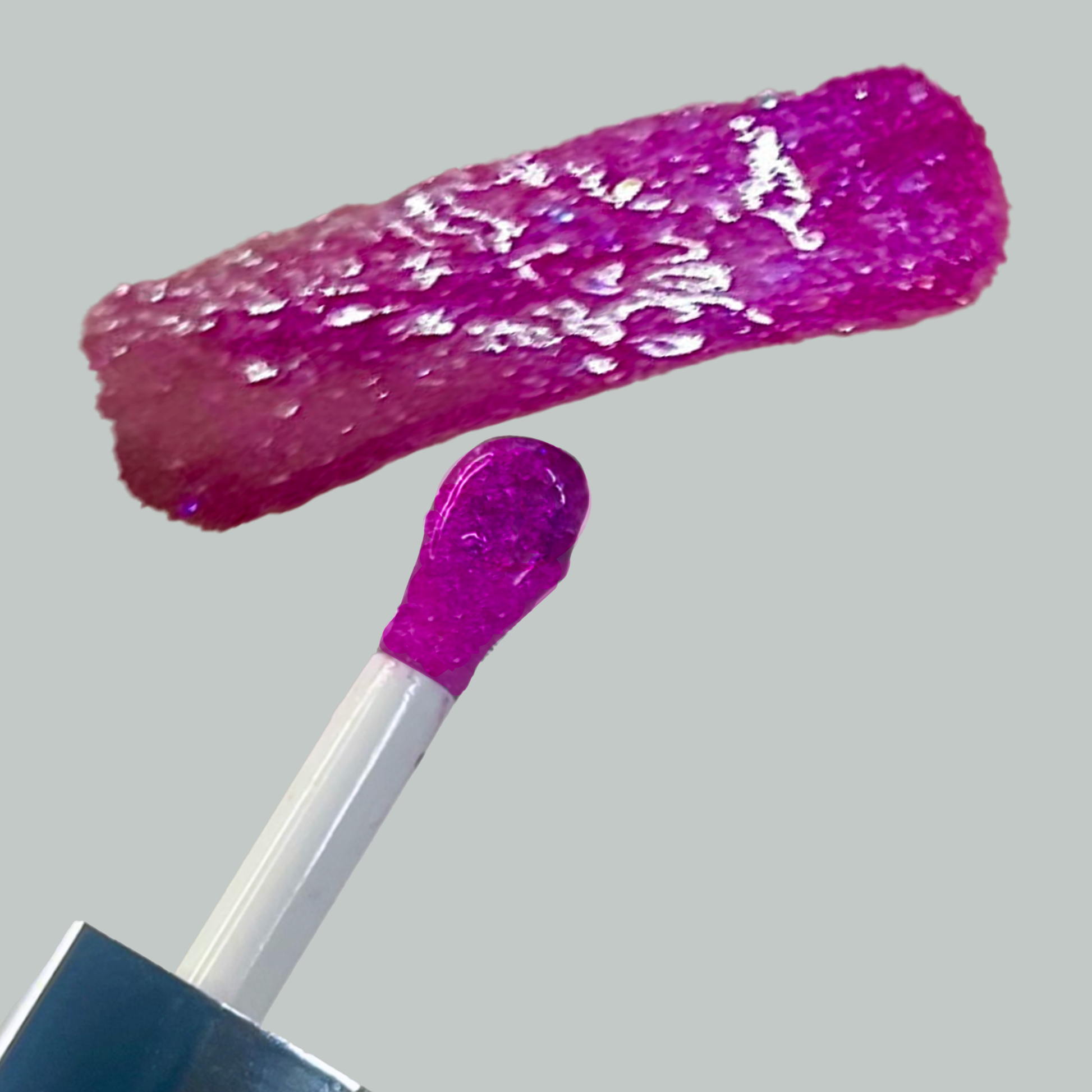 Close-up of a pink glittery lip gloss with applicator on a gray background